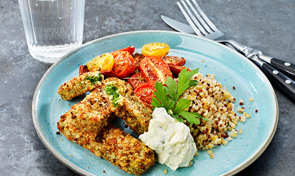 Quinoa, stekte røde og gule tomater, spinatpinner og klatt med basilikumkrem på turkis tallerken. Godt, grønt måltid!