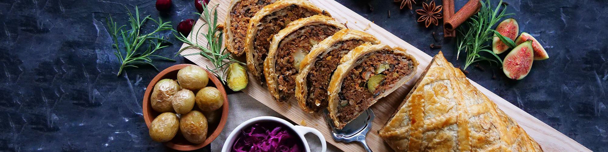 Nøttestek - julemat for vegetarianere. Innbakt nøttefarse i butterdeig, oppskjært i skiver, servert med poteter og rådkål.